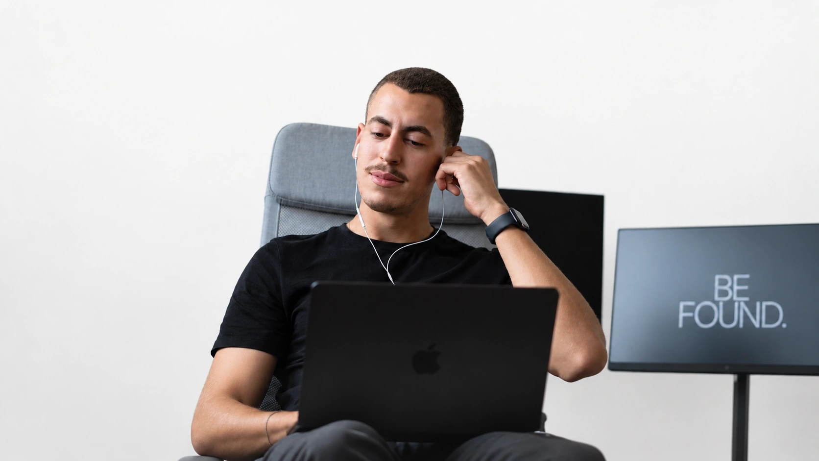 Arthur, fundador da MGL Growth, sentado na cadeira com o notebook, sobre fundo off-white